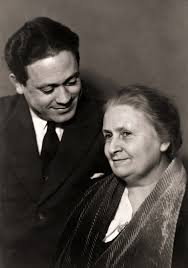Portrait en noir et blanc de Maria Montessori aux côtés de son fils Mario, tous deux regardant dans la même direction avec bienveillance
